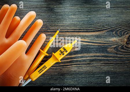 Ein Paar Isolierhandschuhe, elektrischer Tester auf Holzplatte. Stockfoto