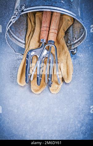 Set aus Handrechen für Garteneimer Sicherheitshandschuhen aus Gabelleder mit metallischem Gartenkonzept. Stockfoto