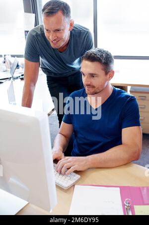 Ich habe den Dreh raus. Zwei Kollegen, die in einem Büro auf einen Computerbildschirm schauen. Stockfoto