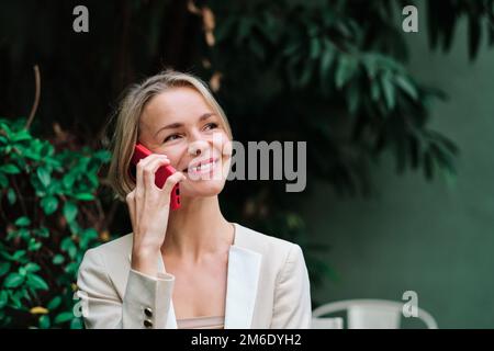 Nahaufnahme einer Geschäftsfrau, die wegsieht und lächelt, während sie telefoniert. Stockfoto