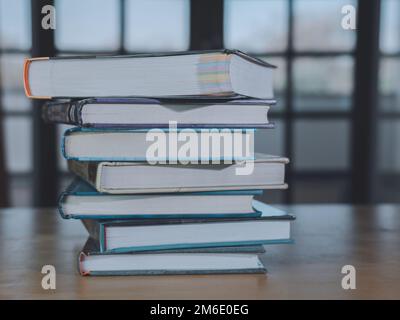 Stapel oder Stapel alter Bücher auf einem Holztisch. Lern-, Ausbildungs- und Studienkonzept. Einer von ihnen öffnet sich mit Kopierraum. Stockfoto