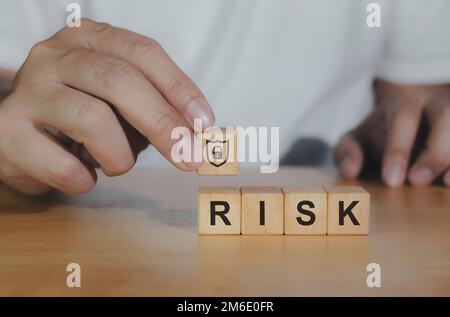 Nahaufnahme Holzblock mit RISIKOSYMBOL für Managementkonzept. Hand of Business entscheidet sich für Shield Icon für Protect Business und erfolgreiche Sieger conce Stockfoto