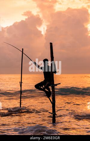 Silhouetten der traditionellen Sri-lankischen Pfahlfischer bei einem Sturm in Koggala, Sri Lanka. Pfahl f Stockfoto