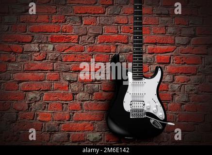 Schwarze elektrische Gitarre auf rotem Backsteinhintergrund Stockfoto