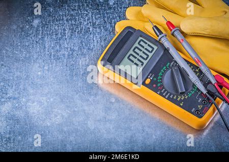 Sicherheitshandschuhe für digitale elektrische Tester zum metallischen Hintergrund-Stromkonzept. Stockfoto