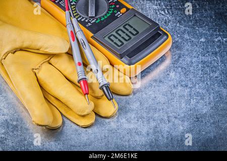 Sicherheitshandschuhe für digitale elektrische Tester auf metallischem Hintergrund. Stockfoto