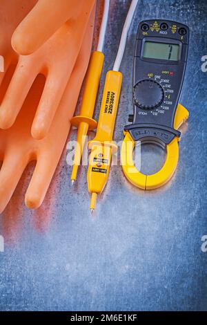 Digitales Amperemeter Elektrotester Isolierhandschuhe aus Gummi auf metallischem Hintergrund Elektrokonzept. Stockfoto