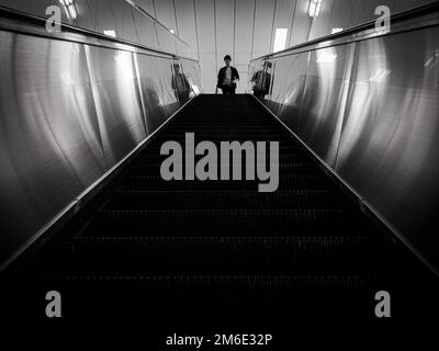 Tokio, Japan - 17 11 19: Ein Mann, der eine Rolltreppe heruntergehen wird Stockfoto