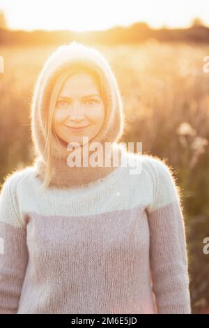 Portrait of Young Pretty Caucasian Happy Girl Woman in Woolen Jacket Bluse und Brown gestrickte Haube posiert im frühen Frühlingswald in Sunny Day. Viel Spaß Stockfoto