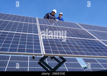 Wartungsingenieur am Solarparkstand auf dem Scherenlift, Inspektion des Solarmoduls und Reparatur Stockfoto