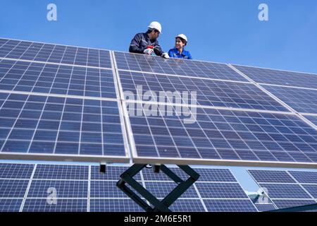 Wartungsingenieur am Solarparkstand auf dem Scherenlift, Inspektion des Solarmoduls und Reparatur Stockfoto