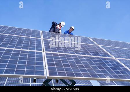 Wartungsingenieur am Solarparkstand auf dem Scherenlift, Inspektion des Solarmoduls und Reparatur Stockfoto