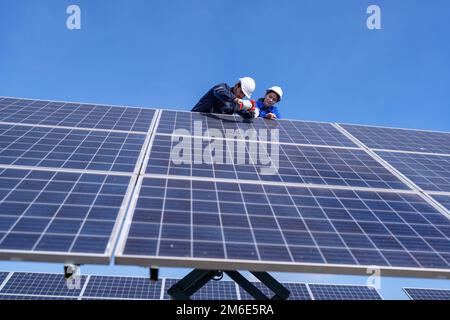 Wartungsingenieur am Solarparkstand auf dem Scherenlift, Inspektion des Solarmoduls und Reparatur Stockfoto