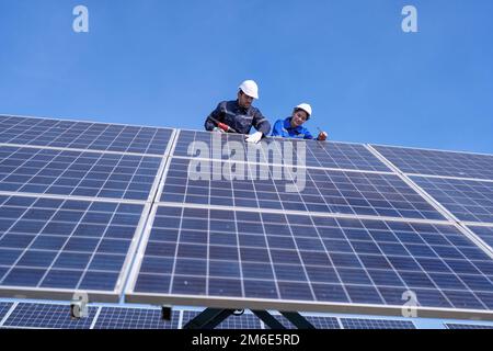 Wartungsingenieur am Solarparkstand auf dem Scherenlift, Inspektion des Solarmoduls und Reparatur Stockfoto