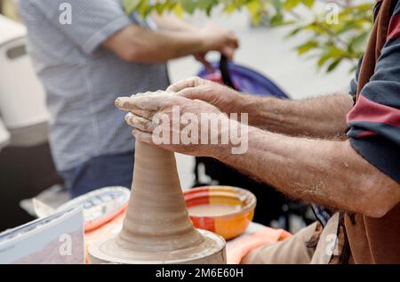Nahaufnahme-Bild-Keramik-Männerhände. Modelliermasse. Handgemachter Topf aus Lehm. Teilansicht der Töpferarbeiten Stockfoto