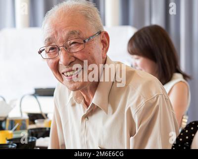 Ein alter Mann, der sich bei einem Familienfest lebhaft unterhielt Stockfoto