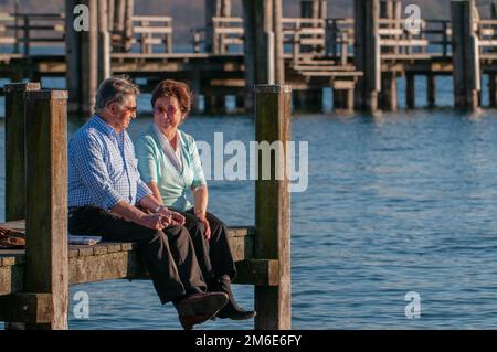 Glückliches älteres Paar, das am Wasser sitzt Stockfoto