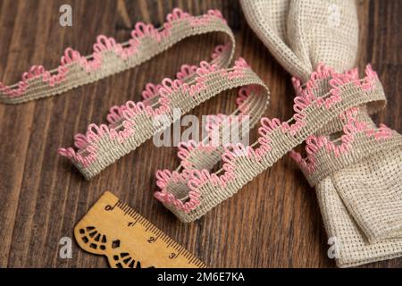 Gestrickte, offene Leinenbänder im ländlichen Stil aus rustikaler Baumwolle Eco auf Holzboden Stockfoto