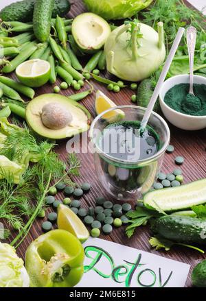 Entgiftungskonzept für grünes Gemüse mit Spirulina-Cocktail. Verschiedene frische grüne Gemüsesorten am Holztisch. Flach verlegt Stockfoto