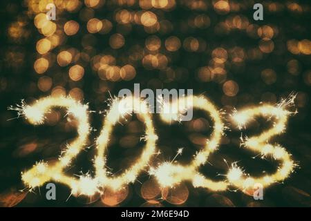 Das Jahr 2023 mit Funken auf dunklem Hintergrund und goldenem Bokeh als gerenderte 3D-Darstellung Stockfoto