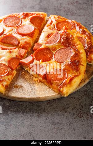 Hausgemachte Peperoni-Pizza mit Wurst, Käse und Tomatensauce, Nahaufnahme auf einem Holzbrett auf dem Tisch. Vertikal Stockfoto