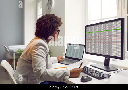 afroamerikanische Geschäftsfrau Buchhalterin, die an einem Laptop mit Tischen im Büro arbeitet. Stockfoto