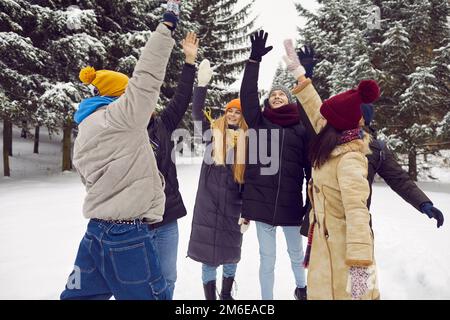 Fröhliche Freunde heben Hand in Hand und genießen Winterferien Stockfoto
