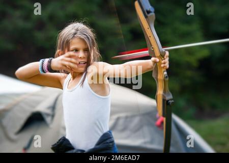 Zigeunermädchen genießt es mit dem Pfeil, der den Bug in einem Glade-Camp verlässt Stockfoto