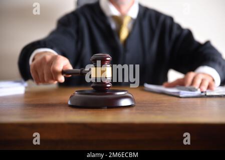 Detail eines Richters, der mit dem Hammer auf eine Holztischverschließung trifft. Vorderansicht Stockfoto