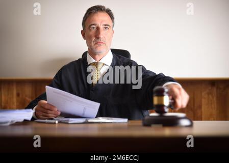 Detail eines Richters, der das Urteil gefällt, indem er mit dem Gavel auf einen Holztisch trifft. Vorderansicht Stockfoto