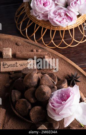 Köstliche Schokoladentrüffel um Zutaten mit rosa Rosenstrauß. Gesunde Süßigkeiten und heutiges Konzept. Stockfoto