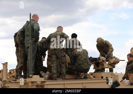 Von rechts, USA Stabschef Steven Brozyna, Panzerkommandeur, 2. Bataillon, 34. Rüstungsregiment, 1. Kampfteam der Brigade, 1. Infanteriedivision, zeigt polnischen Soldaten während des Abrams-Operationsgipfels in Drawsko Pomorskie, Polen, 26. April 2022 ein .50-mm-Maschinengewehr. Die 1. Infanterieabteilung ist unter anderem dem V-Korps zugewiesen, das neben den Alliierten im europäischen Theater arbeitet und weiterhin ein integraler Bestandteil des Demonstrationsvorhabens für die Bereitschaft, Interoperabilität und Fähigkeiten der Allianz ist. Stockfoto