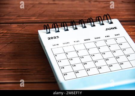 Weißer Tischkalender im Juni 2023 auf Holztisch. Stockfoto