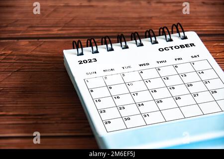 Oktober 2023 weißer Tischkalender mit Holztisch. Stockfoto