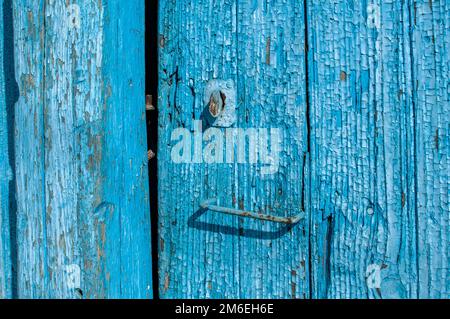 Alte Holzbretter mit zerbröckelter, rissiger blauer Farbe in der Nähe Blauer Hintergrund Stockfoto