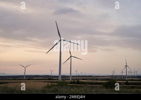 Die Silhouetten der Windturbinenfarm erzeugen am Abend Energie Stockfoto