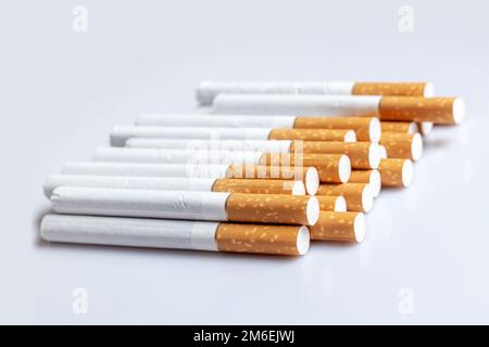 Nahaufnahme einer rauchenden Zigarette. Zigarettenfilterrohre auf weiß. Stockfoto