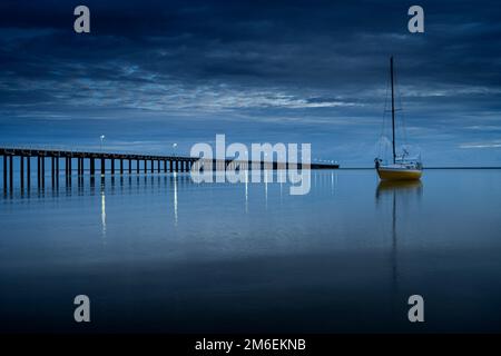 Das Segelboot ankerte in der Nähe des Urangan Pier im frühen Morgenlicht. Hervey Bay, Queensland, Australien Stockfoto