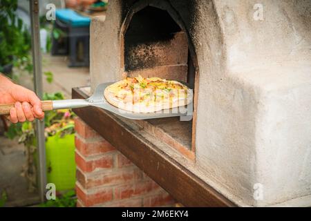 Hausgemachte Pizza auf einer Schaufel, die im Ofen gebacken werden kann Stockfoto