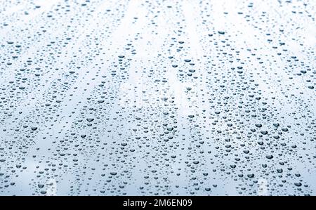 Verschließen Sie Regentropfen auf der Oberfläche der Fahrzeugkarosserie, nachdem sie von der Regenfläche passiert wurden Stockfoto