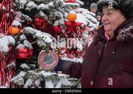 Moskau, Russland. 3. Januar 2023. Eine ältere Frau macht ein Foto mit einem Glas Kaviar, das den Weihnachtsbaum schmückt, auf der Kuznetsky Most Street im Zentrum von Moskau, Russland Stockfoto