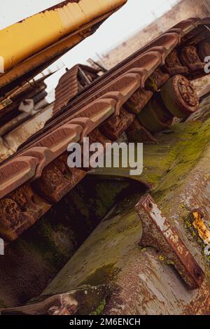 Rusty und Schmutz bedeckt mechanische Caterpillar Track mit Alter Räder und Rollen. Stockfoto