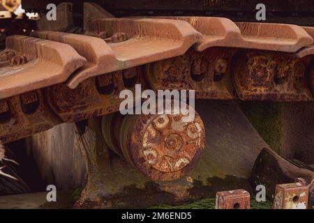 Rusty und Schmutz bedeckt mechanische Caterpillar Track mit Alter Räder und Rollen. Stockfoto