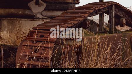 Rusty und Schmutz bedeckt mechanische Caterpillar Track mit Alter Räder und Rollen. Stockfoto