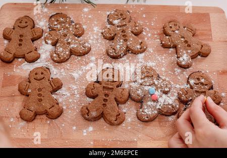 Weihnachten hausgemachte Lebkuchen-Mann-Kekse. Lebkuchenteig für Mädchen und Jungen auf Holzhintergrund. Kinderhand und Gingerbre Stockfoto