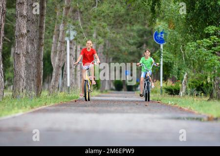 Zwei Freundinnen fahren ein Fahrrad entlang der Wege in der parken Stockfoto