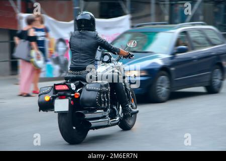 Stilvolles Mädchen in schwarzer Lederkleidung, die auf einem Motorrad fährt. Biker-Motorradfahrerin mit Prote Stockfoto