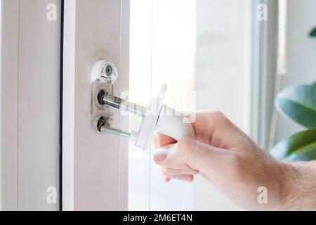 Der Fenstergriff ist gerissen. Der Mann hält es in der Hand, die Eisernen Nadeln sind sichtbar Stockfoto