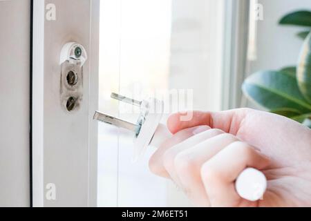 Der Fenstergriff ist kaputt. Den Mechanismus in der Hand halten Stockfoto