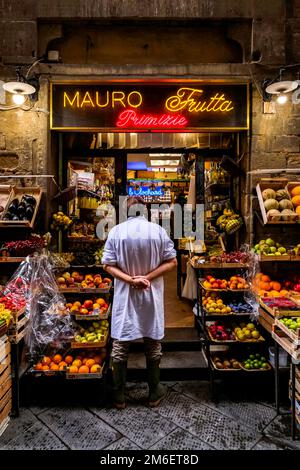 Verkäufer steht in einem bunten Obststand - Florenz, Toskana, Italien Stockfoto